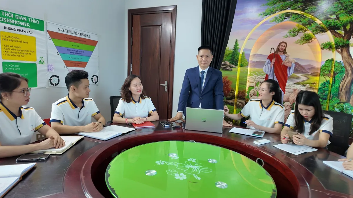 Toàn cảnh buổi họp nhóm quanh bàn tròn, anh Nguyễn Quốc Huy đứng phía sau tại Tâm - Tầm - Tài – Báo cáo tài chính năm