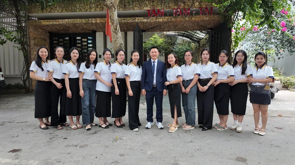 Ảnh tập thể đội ngũ trước cổng có biển Tâm - Tầm - Tài