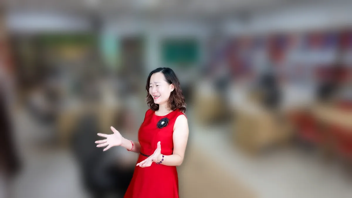 Chị Thảo Nguyễn váy đỏ cầm điện thoại, đứng mỉm cười tại văn phòng Tâm - Tầm - Tài – chia sẻ về có nên thành lập công ty tnhh một thành viên