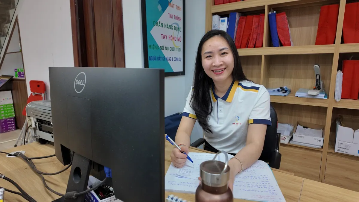 Nhân viên nữ đồng phục trắng ghi chép bên máy tính, mỉm cười tại Tâm - Tầm - Tài – Công ty mới thành lập có được miễn thuế không
