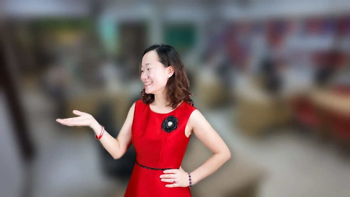 Chị Thảo Nguyễn váy đỏ chống hông, mỉm cười nhìn thẳng tại văn phòng Tâm - Tầm - Tài – chia sẻ về công ty mới thành lập có được miễn thuế không