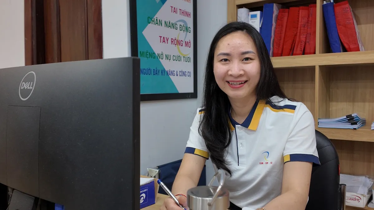 Nhân viên nữ ngồi bàn máy tính mỉm cười nhìn ống kính tại Tâm - Tầm - Tài – Đại lý thuế là gì