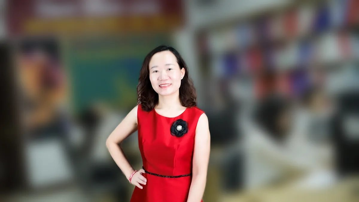 Chị Thảo Nguyễn váy đỏ chống hông, mỉm cười nhìn thẳng tại văn phòng Tâm - Tầm - Tài – chia sẻ về đăng ký nhãn hiệu bị từ chối