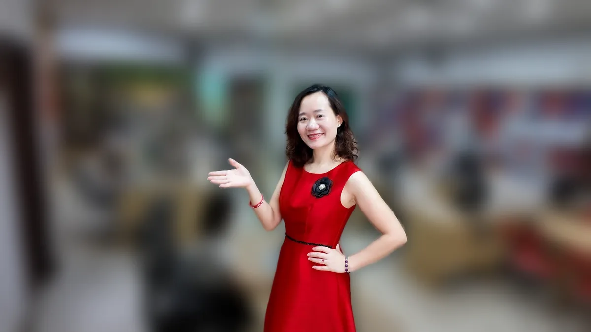 Chị Thảo Nguyễn váy caro đỏ đưa hai tay như giới thiệu, mỉm cười tại văn phòng Tâm - Tầm - Tài – chia sẻ về giáo viên dạy thêm có phải nộp thuế không