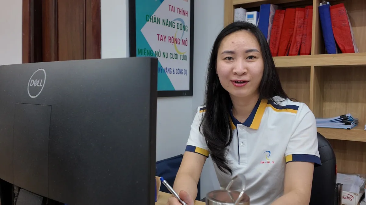 Nhân viên nữ ngồi bàn máy tính mỉm cười nhìn ống kính tại Tâm - Tầm - Tài – Hộ kinh doanh