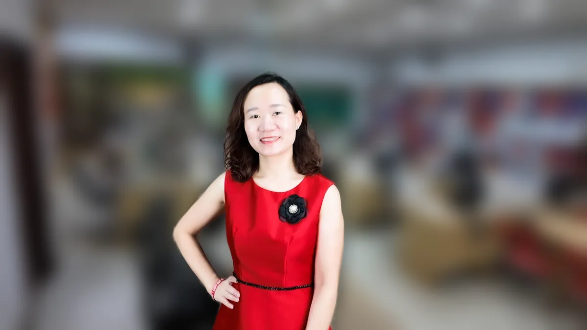 Chị Thảo Nguyễn váy đỏ chống hông, mỉm cười nhìn thẳng tại văn phòng Tâm - Tầm - Tài – chia sẻ về khai thuế hộ kinh doanh dạy thêm