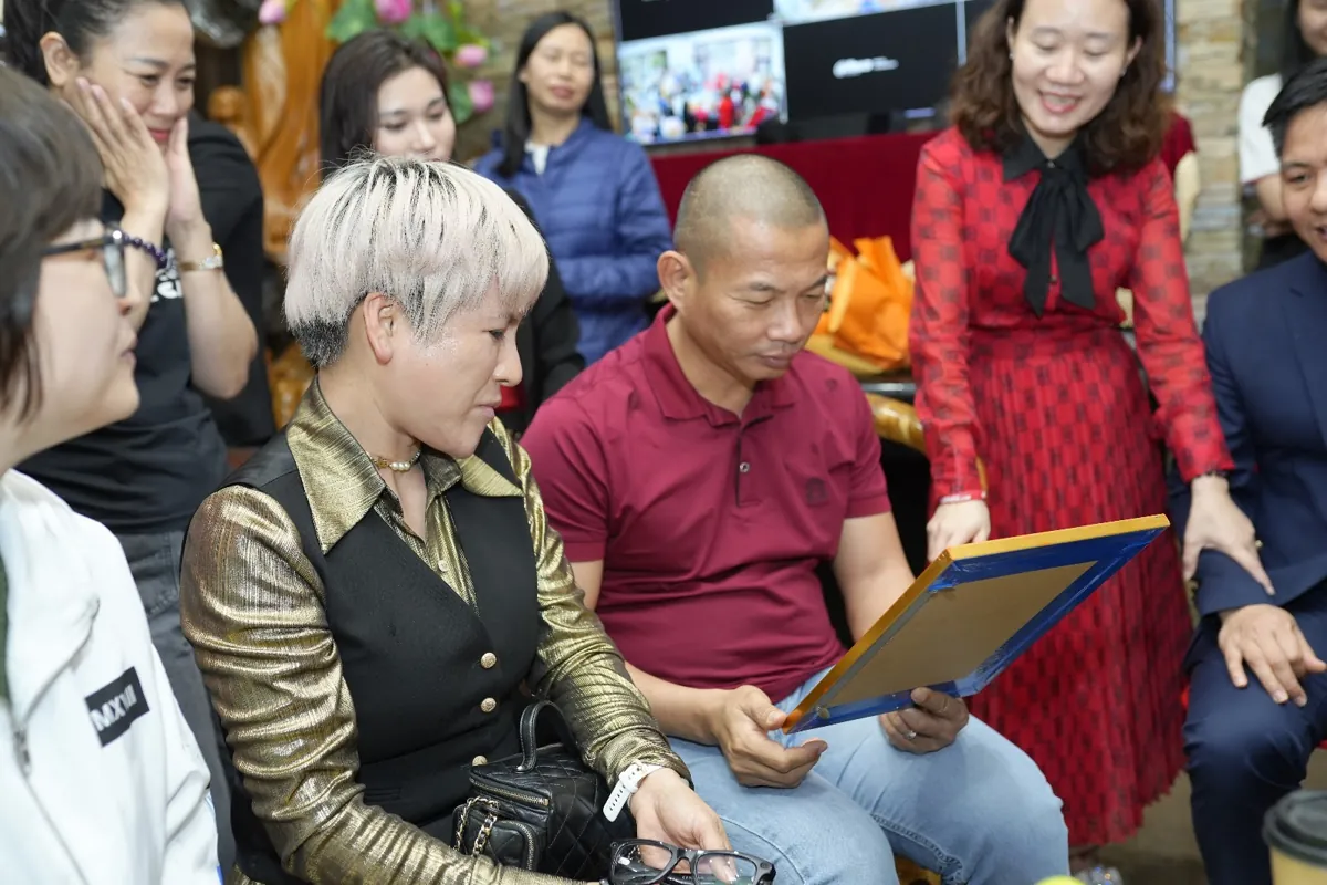 Thầy Long cầm khung ảnh, chị Thảo váy đỏ đứng bên trò chuyện tại Tâm - Tầm - Tài – Khi nào không nên thành lập công ty