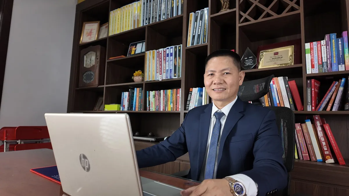 Anh Nguyễn Quốc Huy ngồi làm việc với laptop trước tủ sách tại Tâm - Tầm - Tài – Làm con dấu công ty cần gì