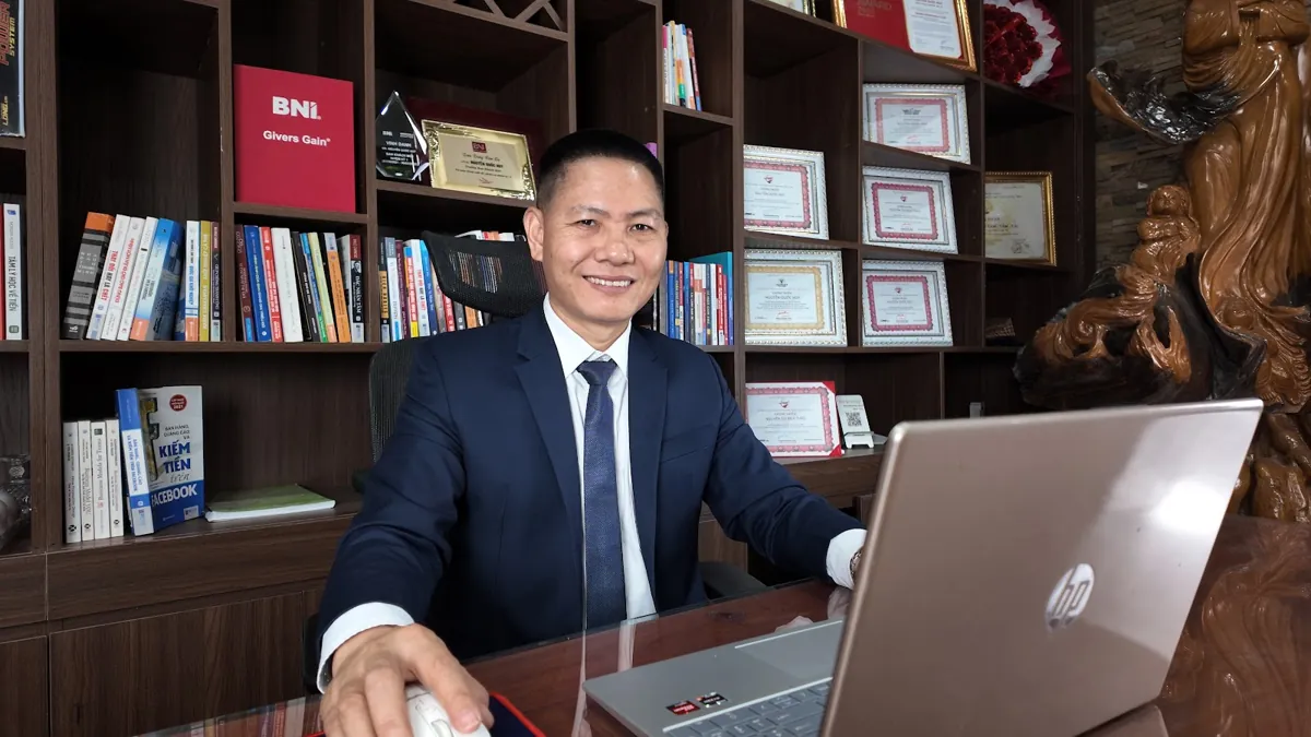 Anh Nguyễn Quốc Huy dùng laptop, kệ sách và giấy khen phía sau tại Tâm - Tầm - Tài – Mở công ty cần giấy tờ gì