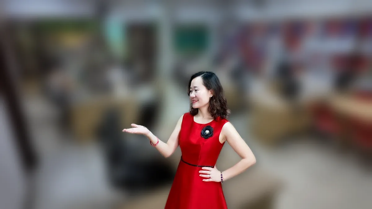 Thảo váy đỏ đứng thẳng mỉm cười tại văn phòng Tâm - Tầm - Tài tại văn phòng Tâm - Tầm - Tài