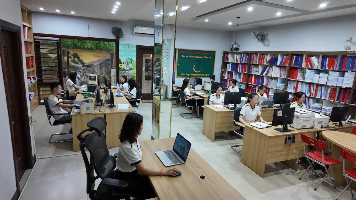 Toàn cảnh văn phòng Tâm - Tầm - Tài, nhân viên ngồi laptop ở tiền cảnh – Mở công ty xây dựng cần gì