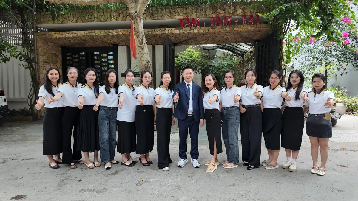Ảnh tập thể đội ngũ trước cổng có biển Tâm - Tầm - Tài – Nâng tầm doanh nghiệp nhỏ