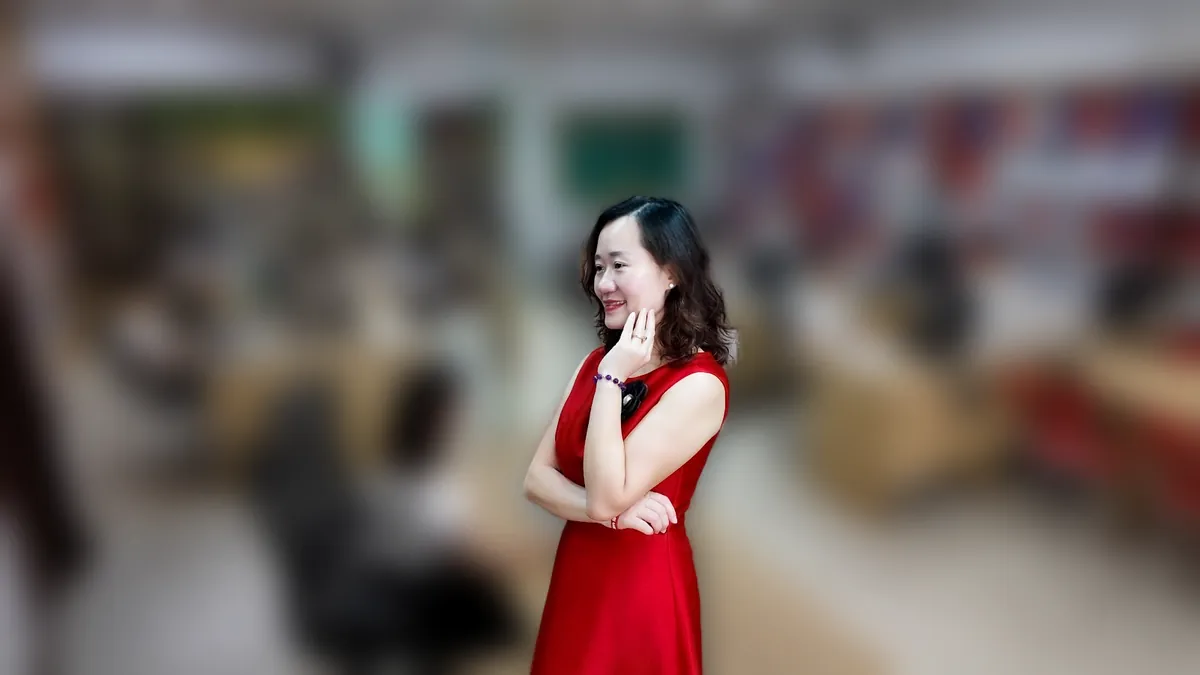 Thảo váy đỏ đứng thẳng mỉm cười tại văn phòng Tâm - Tầm - Tài tại văn phòng Tâm - Tầm - Tài