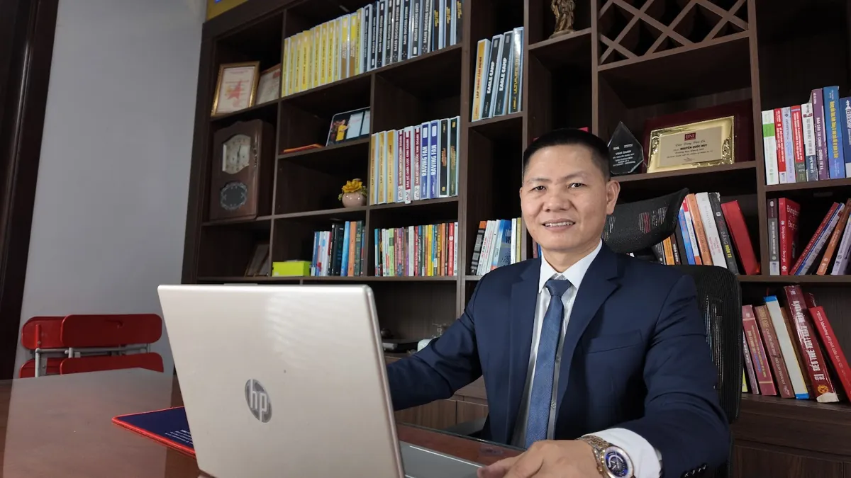 Anh Nguyễn Quốc Huy ngồi bàn làm việc, kệ sách phía sau tại Tâm - Tầm - Tài – Thay đổi đăng ký kinh doanh