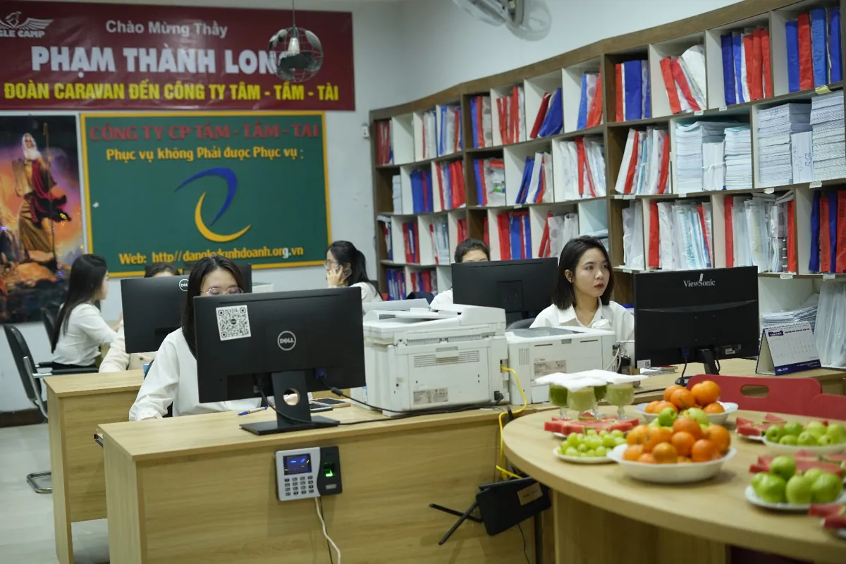 Nhân viên làm việc tại máy tính, kệ hồ sơ phía sau