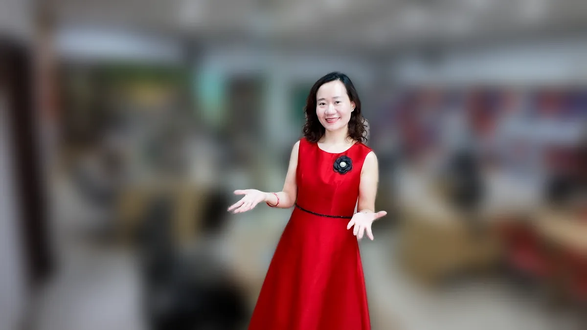 Chị Thảo Nguyễn váy đỏ đứng thẳng mỉm cười tại văn phòng Tâm - Tầm - Tài – chia sẻ về có nên đăng ký hộ kinh doanh không
