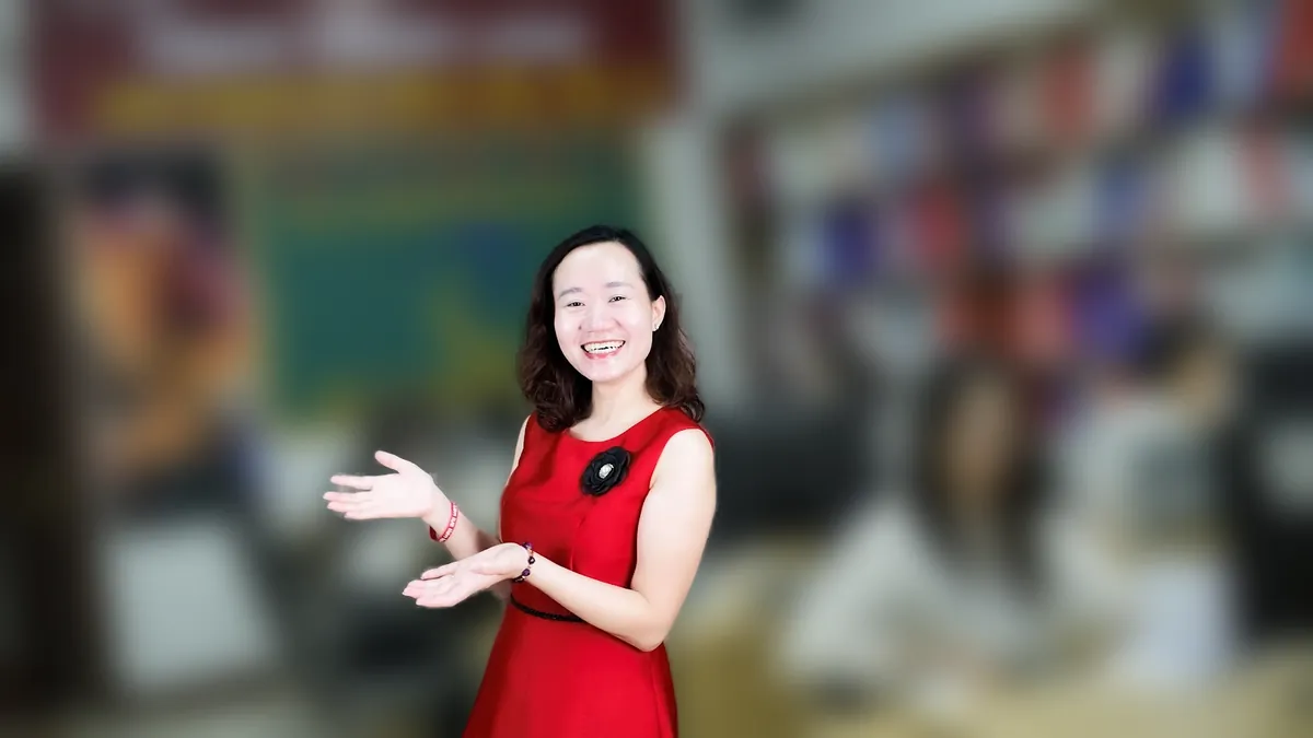 Chị Thảo Nguyễn váy đỏ đưa tay như giới thiệu, mỉm cười tại văn phòng Tâm - Tầm - Tài – chia sẻ về đăng ký hộ kinh doanh online 2026