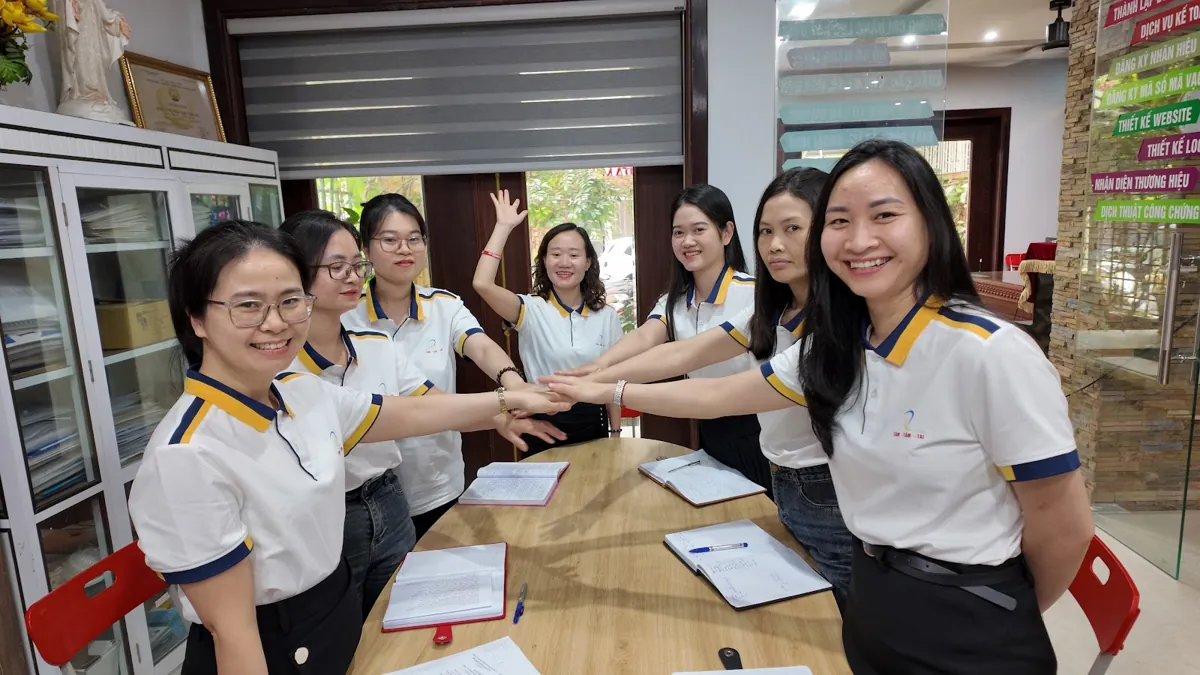 Đội ngũ nhân viên chồng tay đoàn kết quanh bàn họp tại Tâm - Tầm - Tài – Đăng ký hộ kinh doanh trên vneid