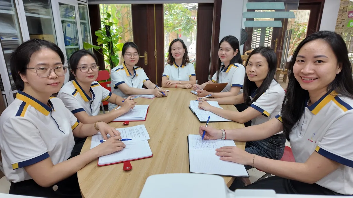 Nhóm nhân viên nữ họp quanh bàn dài, mỉm cười nhìn ống kính tại Tâm - Tầm - Tài – Đăng ký hộ kinh doanh trên vneid
