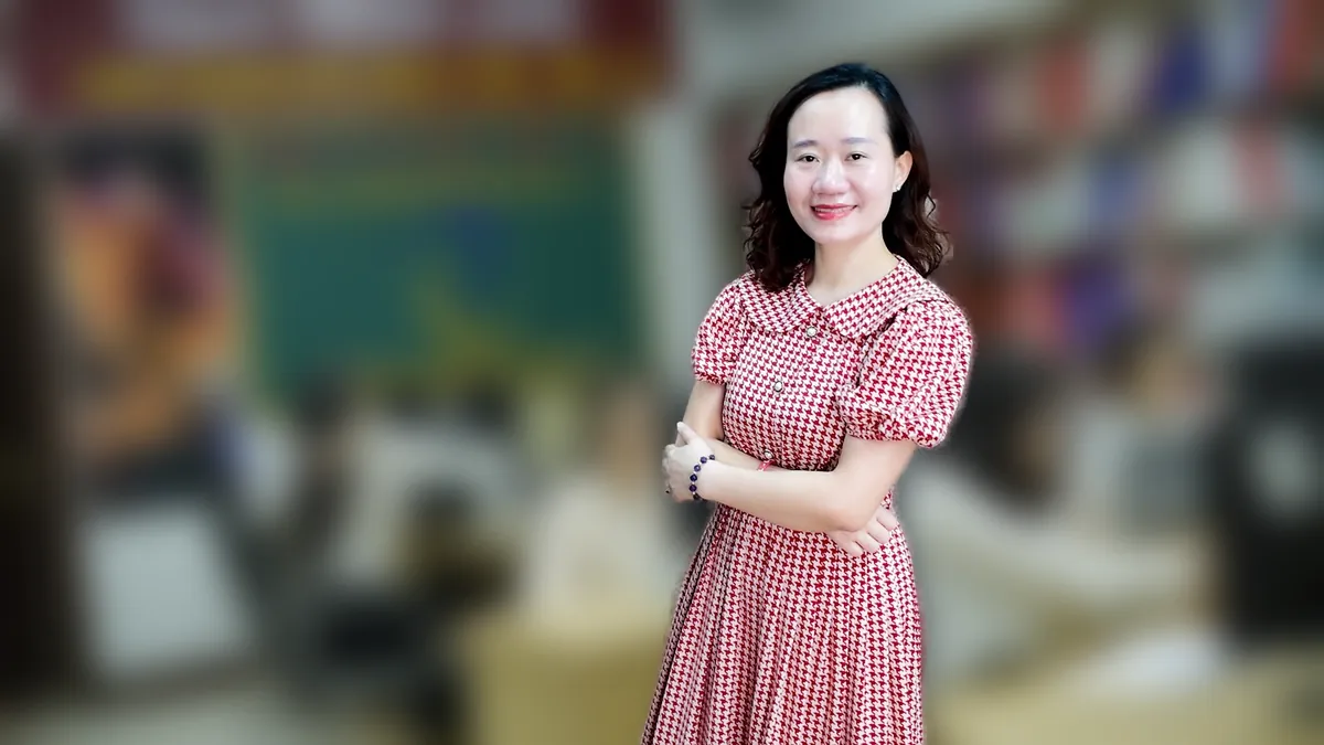 Chị Thảo Nguyễn váy caro khoanh tay, mỉm cười nhìn nghiêng tại văn phòng Tâm - Tầm - Tài – chia sẻ về địa chỉ trụ sở công ty