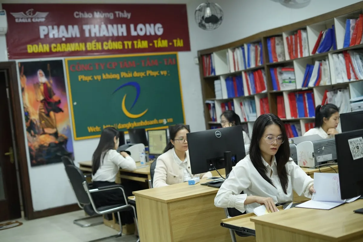 Nhân viên ngồi máy tính trong văn phòng, kệ hồ sơ đầy