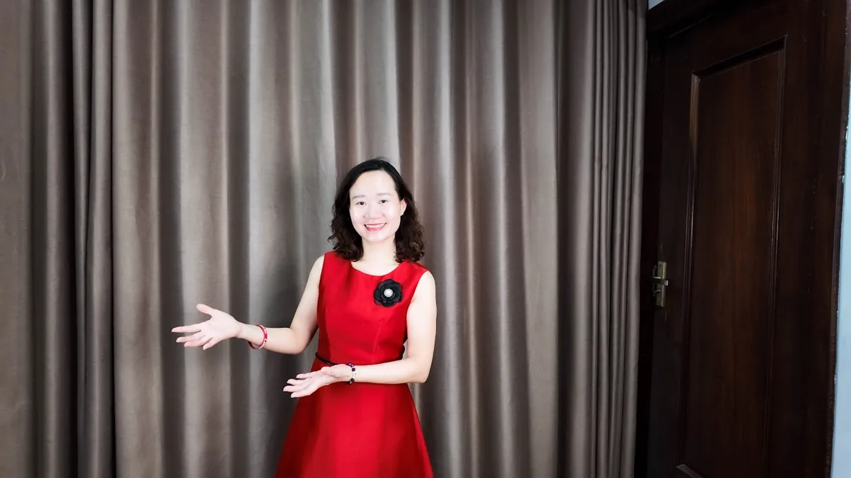 Thảo váy đỏ đưa tay như giới thiệu, mỉm cười