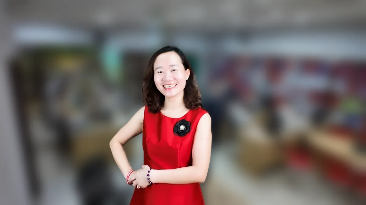 Chị Thảo Nguyễn váy đỏ chống hông, mỉm cười nhìn thẳng tại văn phòng Tâm - Tầm - Tài – chia sẻ về thủ tục chuyển đổi hộ kinh doanh thành công ty